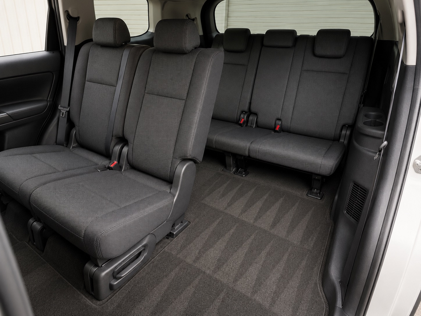 The same SUV rear rows from the same angle after cleaning, upholstery uniform and carpet vacuumed with visible extraction lines